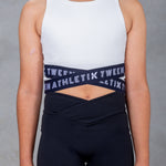 A young female model wearing a black crop top with 'ATHLETIK TWEEN' text on it.