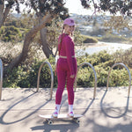 Tween in pink athletic wear skateboarding outdoors with a scenic background