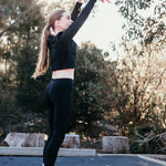 Tween stretching outdoors on a red surface with trees in the background